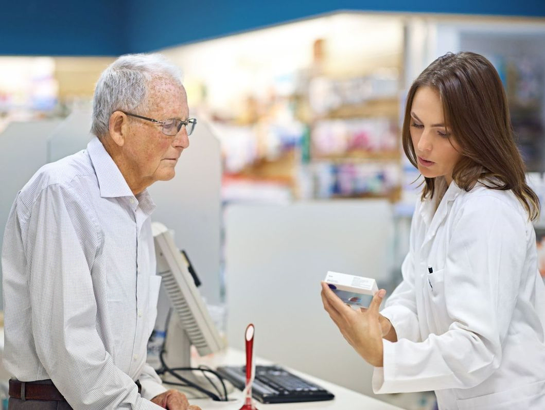 farmacéutica atendiendo a cliente anciano